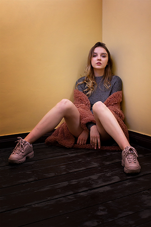 A stylish pretty young russian girl sitting on floor.