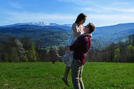 A couple huging in country side with snowed mountain on the background.