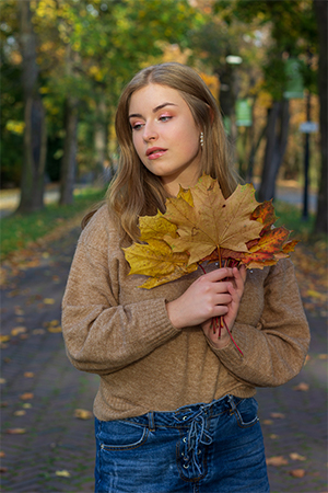 Autumn portrait of Ewa holding dry leaves.