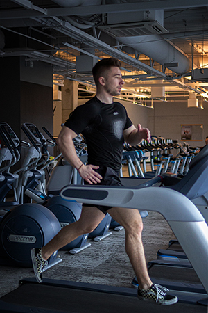 A young athletic guy exercise running in the gym.