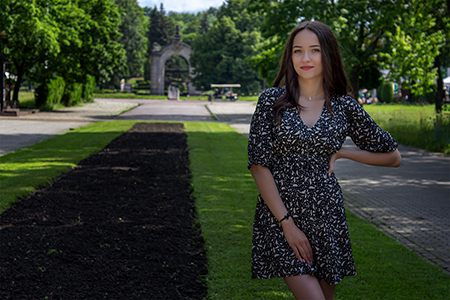 A brunette girl posing in a green park.