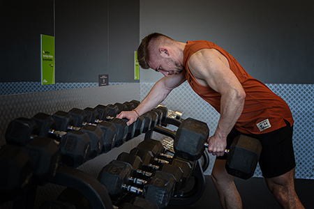 A musceled young man lifting weights in the gym.