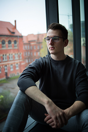 Portrait of a young man with glasses by the window.