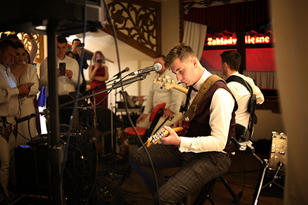 A young man playing guitar infront of young people filming him with mobile phones.