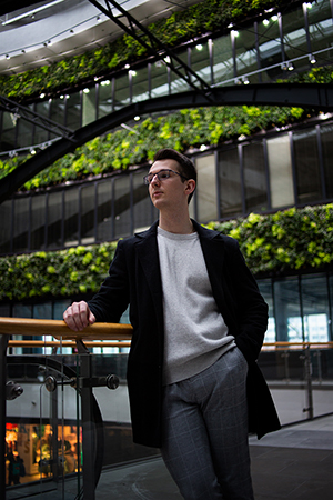 A portrait of a young man in a shopping mall interior.