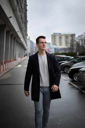 A young man walking in urban city street a cloudy day.