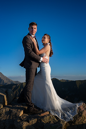 Bride hugs groom in a mountain landscape.