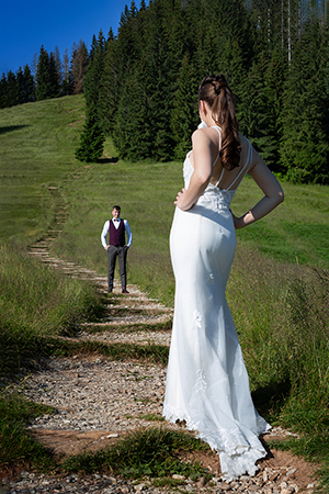 Bride is looking the groom from distance in a mountain photography session.