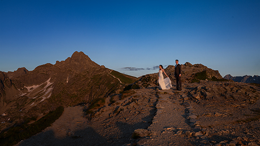 Wedding couple staring at the horizon at late evening in a rocky landscape.