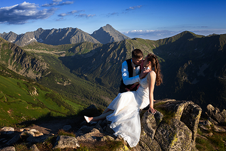 Groom huging his wife in her wedding dress at Tatra mountains.