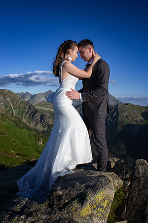 Bride in wedding dress is huging groom in the Tatra mountais.